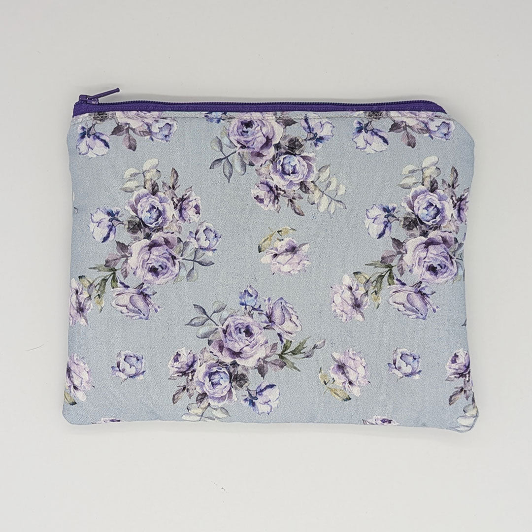 Rose patterned pouch with purple zipper on a light blue background